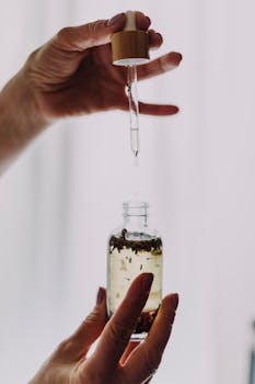 Close-up of hands using a dropper with an essential oil bottle, perfect for wellness themes.