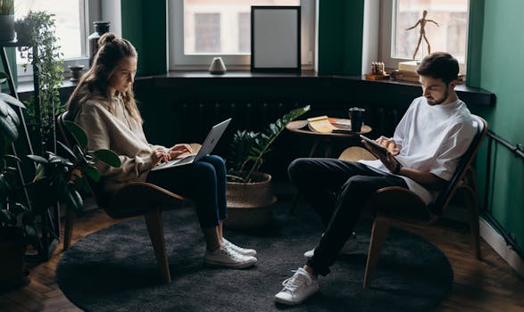 Two remote workers collaborating in a cozy home office with laptops and plants, creating a modern workspace atmosphere.