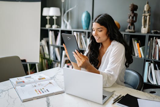 Woman working with a digital tablet and laptop in a modern office environment.