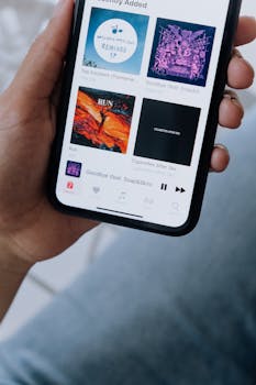 Close-up of a hand holding a smartphone displaying a music playlist on screen.