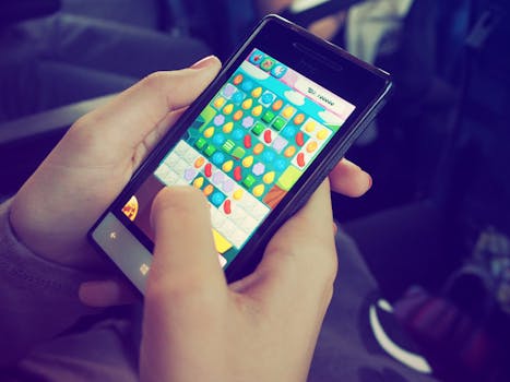 Hands holding a smartphone with a colorful puzzle game on the screen, displaying modern technology.